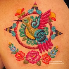 the back of a woman's shoulder with colorful embroidery work on her body and chest