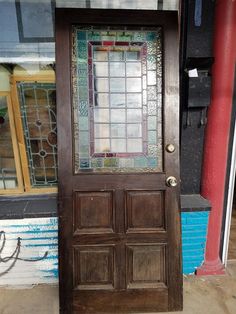 an old wooden door with stained glass on the top and bottom panel, in front of a storefront