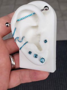 a person is holding a fake ear with blue stones