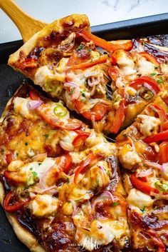 a pizza sitting on top of a pan covered in lots of toppings next to a wooden spatula