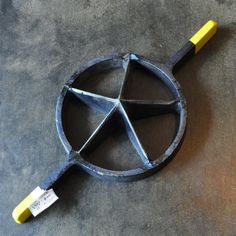 a metal object with a yellow handle sitting on the ground next to a gray floor