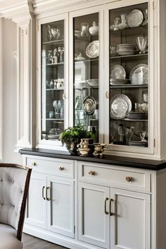 a white china cabinet with glass doors and black counter top in a dining room area