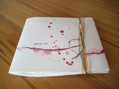 an open notebook on a wooden table covered in red and pink paint splattered paper