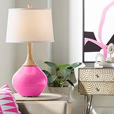 a pink lamp sitting on top of a table next to a white dresser and chair