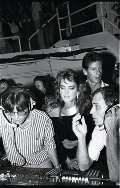 black and white photograph of two people dancing at a party with palm trees in the background