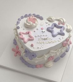 a heart shaped cake decorated with pastel icing and decorations on top of a white card