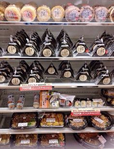 an assortment of baked goods on display in a bakery case, with labels and price tags