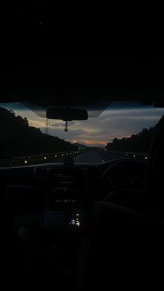 the sun is setting in the distance as seen from inside a car's dashboard