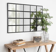 a wooden table topped with a plant and mirror