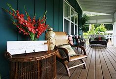 a porch with wicker furniture and flowers on the front steps, along with blue painted walls