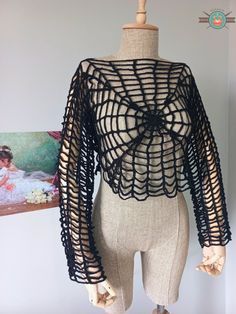 a mannequin wearing a black crochet top with an openwork design