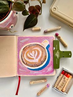 an open notebook with coffee and crayons on it