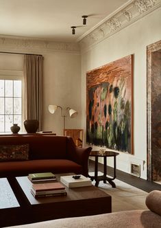 a living room filled with furniture and a large painting on the wall above it's coffee table