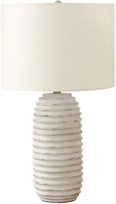 a white ceramic lamp with a beige shade on it's base and a light bulb in the middle