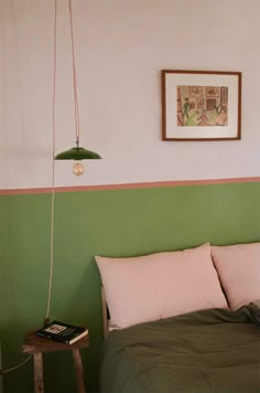 a bed with green and pink sheets in a bedroom next to a painting on the wall