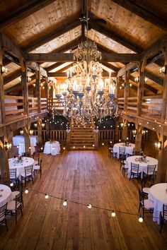 the inside of a barn with chandeliers and tables set up for an event