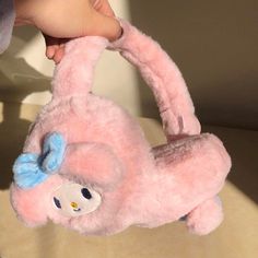 a pink stuffed animal with a blue bow on it's head is being held by someone