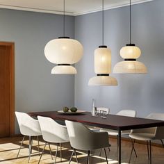 a dining room table with chairs and lights hanging from it's ceiling over it