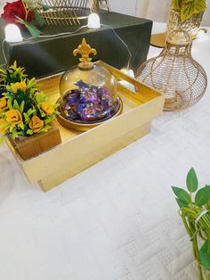 a table topped with vases filled with flowers next to a wooden box on top of a table