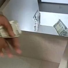 a hand is holding money in front of a mirror with the reflection of another person on it