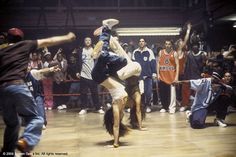 two people doing tricks on the floor in front of a group of young men and women