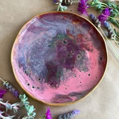 a pink and purple plate sitting on top of a table next to lavender flowers in front of it