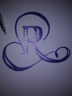 the letter r is drawn with purple glitter on white paper next to a fountain pen