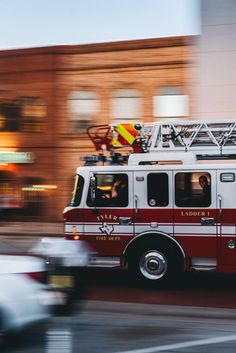 a firetruck driving down the street in front of some buildings with cars passing by