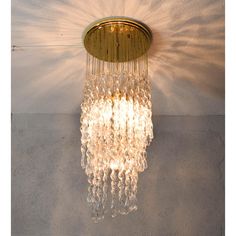 a chandelier hanging from the ceiling in a room with white walls and concrete flooring