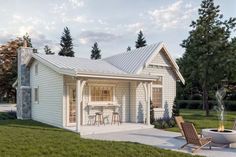 a small white house sitting on top of a lush green field next to a fire pit