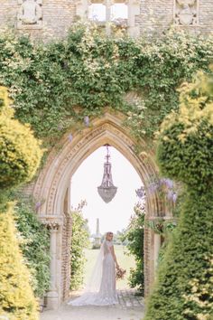 a bride standing in an archway with greenery around her