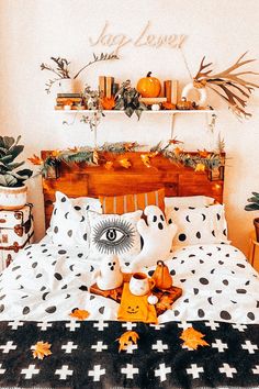 a bed with black and white sheets, orange pillows and decorations