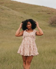 a woman is standing in the grass with her hands on her head and looking at the camera