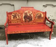 an old red bench painted with images of animals and people on it in the snow