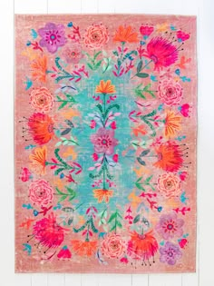 a pink rug with colorful flowers on the front and back, against a white wall