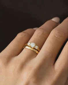 a woman's hand wearing a gold ring with three stones on it and the middle finger