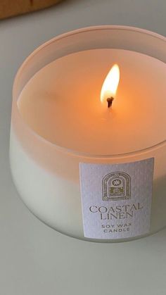 a lit candle sitting on top of a white table next to a piece of bread