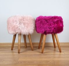 two wooden stools with pink and purple fur on them sitting next to each other