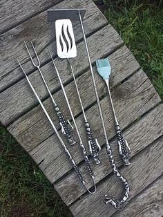 four barbecue tools sitting on top of a wooden table next to a grilling spatula