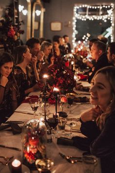 a group of people sitting at a long table with candles in front of their faces