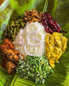 a plate with rice, meat and vegetables on top of a leafy green surface