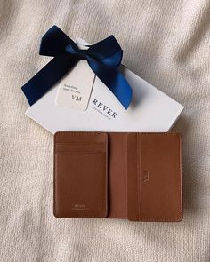 a brown wallet with a blue bow on top of it next to a card case