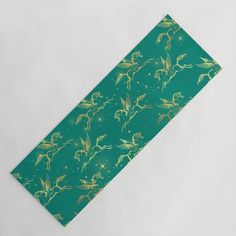 a green and gold patterned table runner on a white surface with an image of flowers in the background