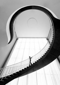 black and white photograph of a person standing on the top of a spiral stair case