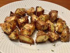 a white plate topped with cooked potatoes on top of a wooden table