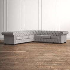 a gray couch sitting on top of a hard wood floor next to a white wall