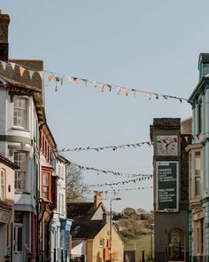 there are many buildings on the street with flags strung above them and a clock tower in the distance