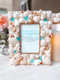 there is a frame with seashells on it and a candle in the background