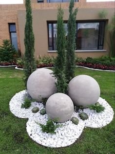 three large balls sitting in the middle of a garden