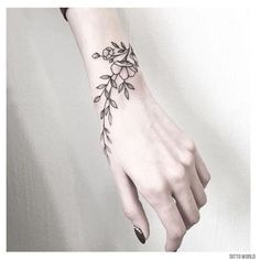 a woman's hand with a black and white flower tattoo on the left wrist